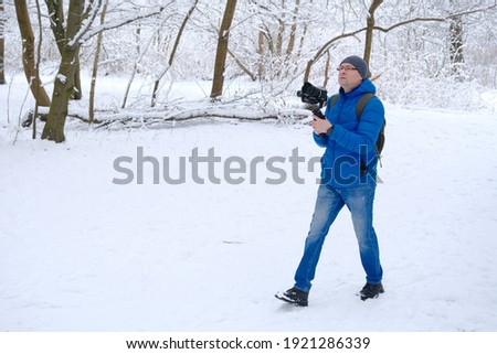 professional cameraman with camera taking shoots in snow forest