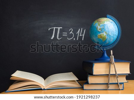 The Greek letter Pi the ratio of the circumference to its diameter, is drawn in chalk on a black school board with books, a globe and a compass in honor of the international number Pi for March 14 Royalty-Free Stock Photo #1921298237