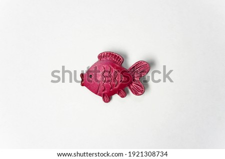 An object on a white background - a metal badge with the image of a fish