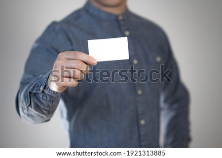 A man holds a white business card. A paper in the hands of a man. Prepared for your text. Isolated on a gray background.