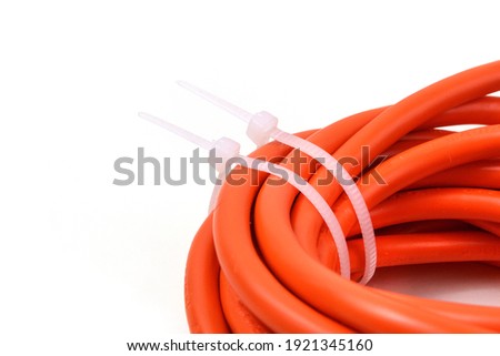 White cable ties on orange cable. Close up. Royalty-Free Stock Photo #1921345160