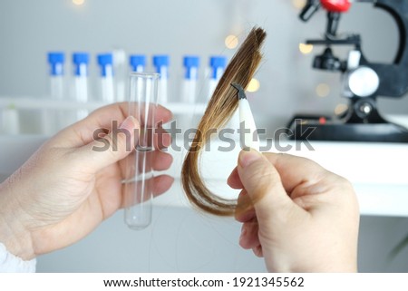 laboratory assistant examines a hair sample, curls in a package for research by genetic research in laboratory, trichologist conducts test, concept of DNA analysis, establishing paternity Royalty-Free Stock Photo #1921345562