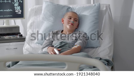 Teen boy patient lying in hospital ward. Sick bald kid with nasal tube lying in hospital bed after chemotherapy Royalty-Free Stock Photo #1921348040