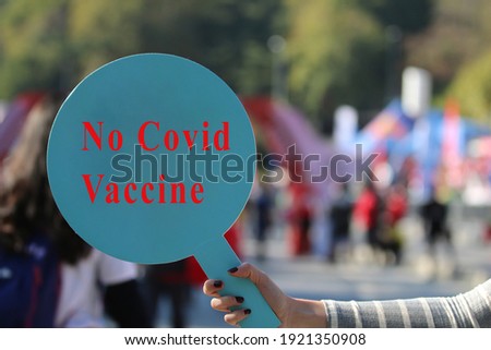 front view, woman holding banner with anti-vaccination inscription