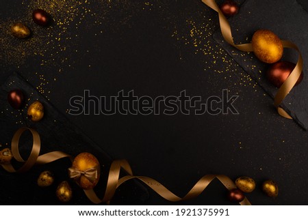 Golden luxury easter eggs and ribbon composition boder frame on black stone background with copy space for text card