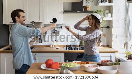 Wide banner panoramic view of happy millennial man and woman spouses have fun play with kitchen appliances cooking together. Overjoyed funny young Caucasian couple have fun enjoy morning at home.
