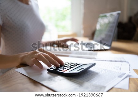Crop close up of woman calculate on calculator manage family budget make payment on computer. Female busy take care of household expenses expenditures, paying bills on laptop online. Saving concept. Royalty-Free Stock Photo #1921390667
