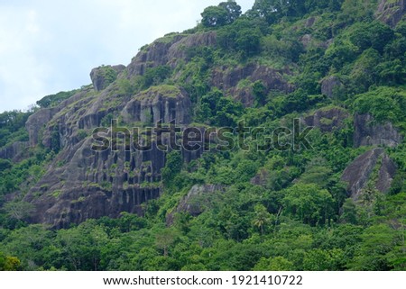 rock formations in the ancient Nglanggeran volcano that were formed millions of years ago. overgrown by green trees typical of the tropics. High ancient black stone towering.