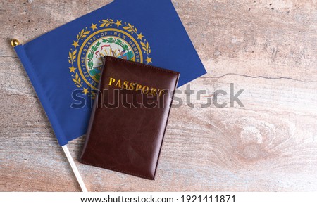 Passport and a New Hampshire flag on a wooden background. Travel concept