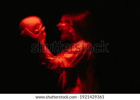 blurry terrible portrait of a ghost witch girl with a dead man's skull in her hands on a dark background