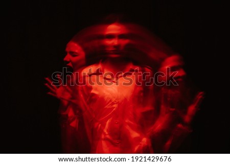 abstract blurry female portrait of a psychotic with bipolar and schizophrenic disorders with red illumination on a black background Royalty-Free Stock Photo #1921429676