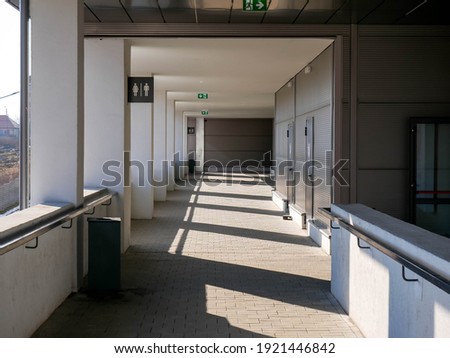 Empty outdoor corridor at city mall with exit sign on a bright sunny spring day.