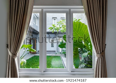 Large three pane window looking on summer backyard with tropical garden