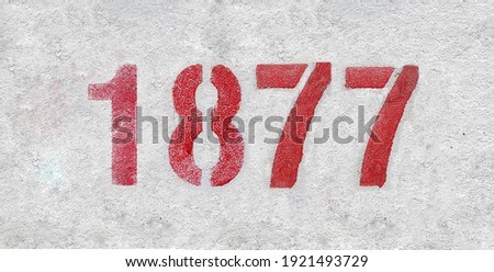 Red Number 1877 on the white wall. Spray paint.