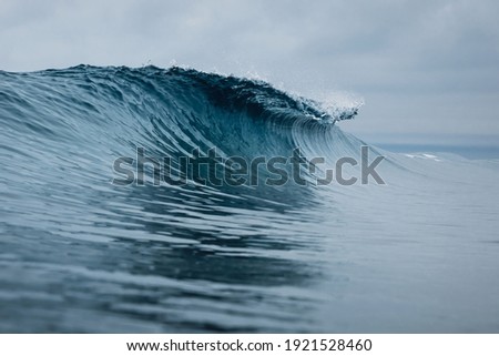 Perfect ocean waves with blue water cloudy sky.