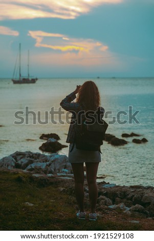 woman taking picture of the yacht in bay on sunset. copy space. summer time