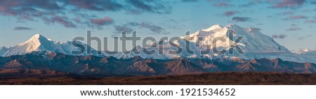 The Alaska Range remains covered in snow during all times of year due to its high elevation. The snow capped mountains provide a beautiful contrast from the view at Wonder Lake.  Royalty-Free Stock Photo #1921534652