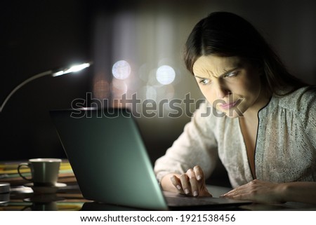 Suspicious entrepreneur woman checking laptop content late hours in the night at home Royalty-Free Stock Photo #1921538456