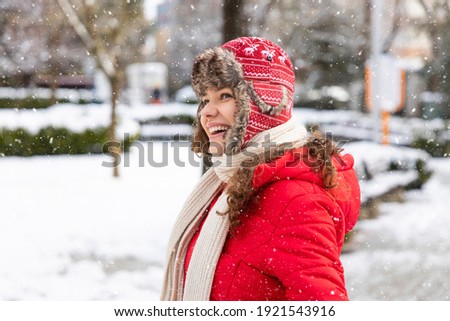 Young smiling woman enjoying a winter snowy day in the city
