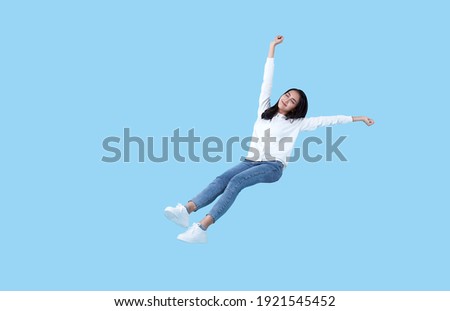 Young beautiful smiling asian girl floating in mid-air relaxing isolated on blue background.  Royalty-Free Stock Photo #1921545452
