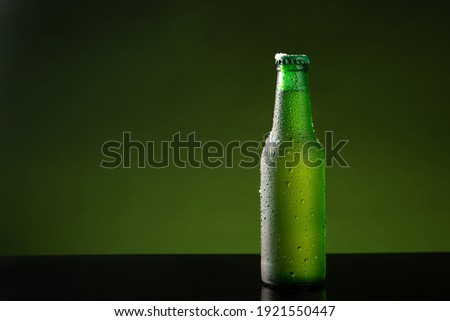 Bottle of cold beer with water drop on green background with copyspace.
