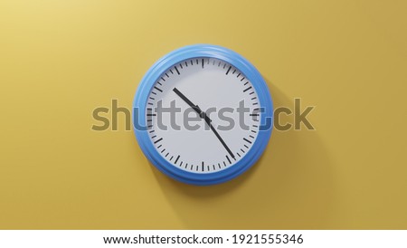 Glossy blue clock on a orange wall at twenty-four past ten. Time is 10:24 or 22:24 Royalty-Free Stock Photo #1921555346