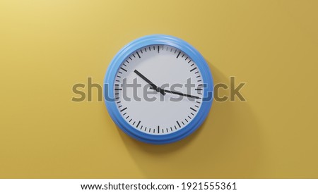 Glossy blue clock on a orange wall at seventeen past ten. Time is 10:17 or 22:17 Royalty-Free Stock Photo #1921555361