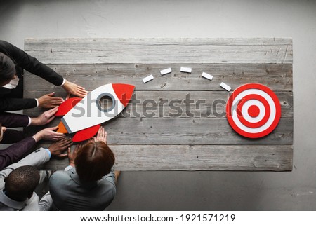Team of business people with rocket as a sumbol of high risky goals targeting at red target at meeting table Royalty-Free Stock Photo #1921571219