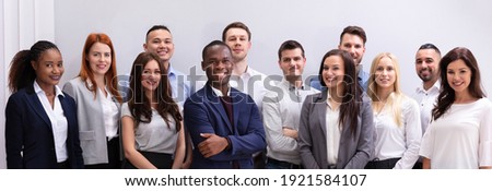 Group Of Young Successful Multi-ethnic Businesspeople Standing In Office Looking At Camera