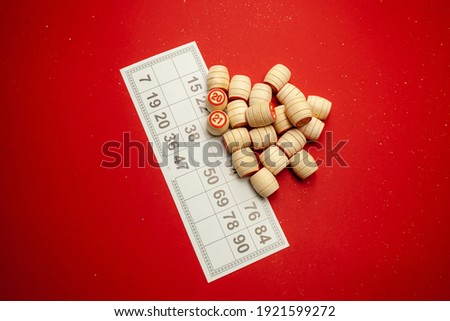 Wooden bingo kegs, on a red background in a red bag, for playing bingo. A way to spend time at home. A game of chance, card with numbers. . High quality photo