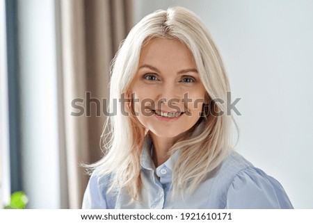 Smiling sophisticated 50s middle aged blond business woman looking at camera. Happy mature elegant old lady professional businesswoman posing at home office. Headshot close up portrait Royalty-Free Stock Photo #1921610171