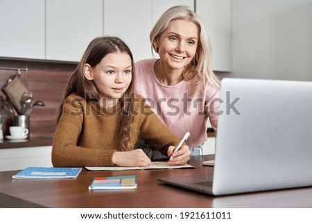 Teen girl distance learning virtual distance online class on video call virtual lesson with mother, studying at home using laptop computer. Parent or tutor helping child daughter with remote education Royalty-Free Stock Photo #1921611011