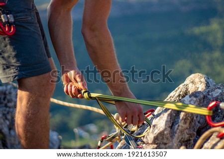 unrecognisable young adult man holding on to ropes. young male securing ropes to the rocks for climbing close up