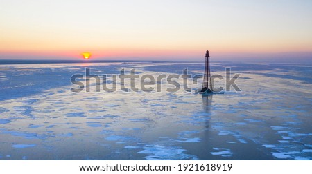 The Adziogol lighthouse on the  Dnieper river frozen in ice at sunset. The tallest lighthouse of Ukraine. Aerial view. Drone photo
