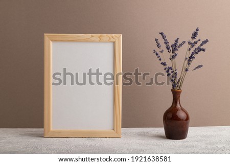 White wooden frame mockup with lavender in ceramic vase on beige paper background. Blank, vertical orientation, still life, copy space.