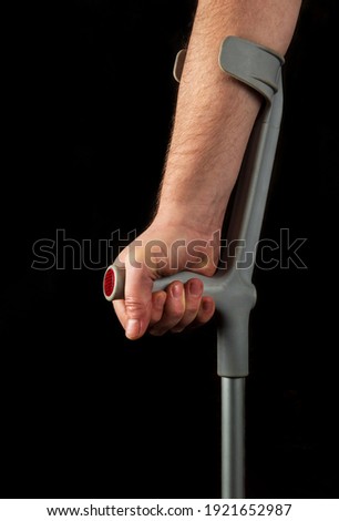 Close up of person hand with forearm crutches. Black isolated background vertical image. Side view