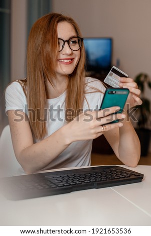 Using smartphone and credit card online shopping. Woman using mobile phone app playing game, shopping online, ordering delivery relax on sofa.