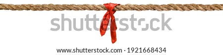Long tug of war rope pulled tight, with red ribbon tie. Concept of conflict, competition, or rivalry. Isolated on white. Royalty-Free Stock Photo #1921668434