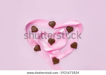 Milk chocolate and pink heart-shaped ribbon. Sweet gifts for Valentine's Day. Selective focus
