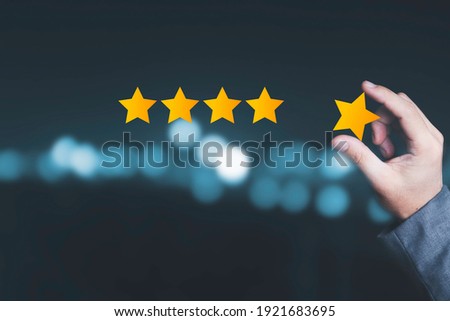 Customer satisfaction and product service evaluation concept , Hand holding and put yellow star to five stars with copy space. Royalty-Free Stock Photo #1921683695