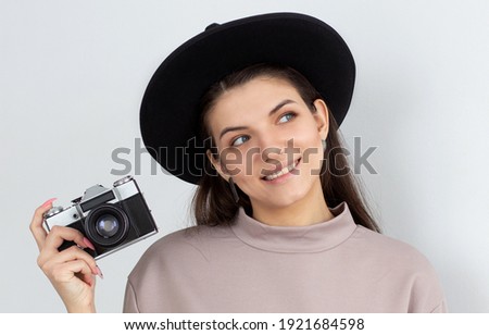 Portrait of a smiling girl with a camera in hand on a white background. Isolated studio