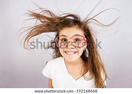 Closeup portrait happy, smiling , excited, funny looking, little girl with big glasses, messy hair, isolated dark blue background. Positive human emotion, facial expression, attitude, reaction