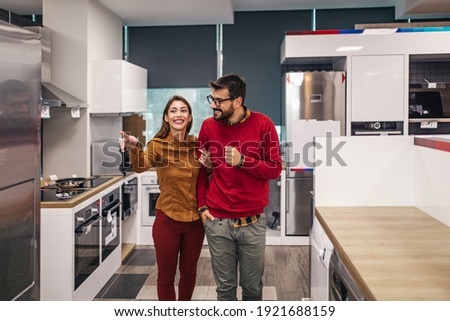 Young couple, satisfied customers choosing fridges in appliances store. Royalty-Free Stock Photo #1921688159