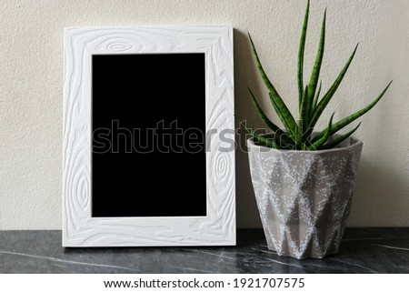 Empty white vintage wooden frame standing over white cement wall and black marble floor with shadow background, copy space for mock up and template