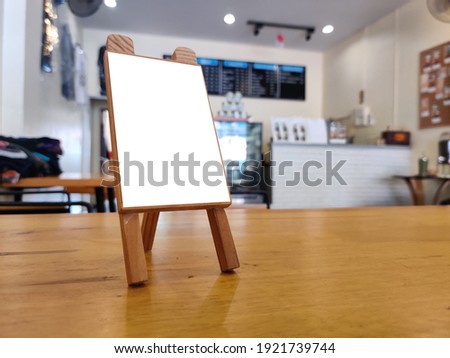 mockup of a food menu list stand on wooden table inside cafe with people and family sitting having dinner during evening sunset, tent card