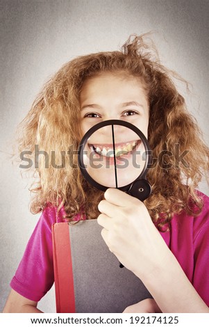 Closeup picture, portrait funny, smiling little, cute teenage girl with magnifying glass showing teeth, half white, half yellow isolated dark grey background. Dental care, hygiene concept, whitening