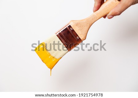 Hand with paintbrush with yellow paint drips off the brush Royalty-Free Stock Photo #1921754978