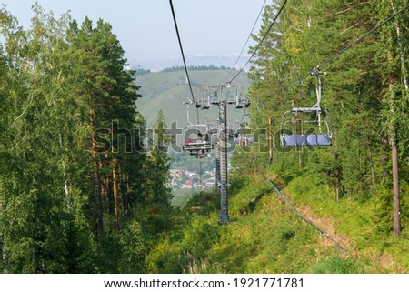 Chairlift in the mountains. Cable car supports. Summer season, green trees, grass. Summer mountain resort concept.