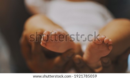 Black father playing with baby feet. Close up. High quality photo