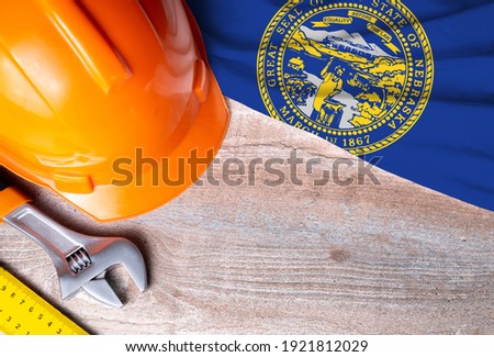 Nebraska flag with different construction tools on wood background, with copy space for text. Happy Labor day concept.